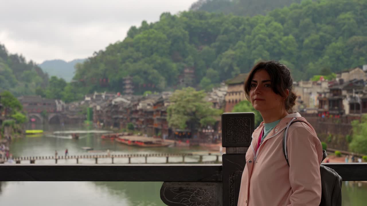 Mulher observando a paisagem da Cidade Antiga de Fenghuang, China, da Ponte da Neve