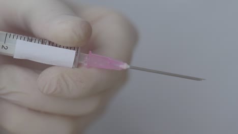 la enfermera aprieta el émbolo de una jeringa llena de vacuna, primer plano