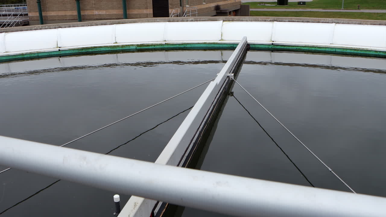 Clarifier pond at a wastewater treatment plant processes water as solids settle and liquid flows, capturing the industrial treatment process in motion