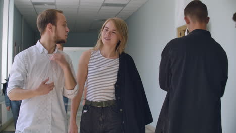 A-group-of-students-walk-along-the-corridor-of-the-university-school-college-communicate-talk-and-smile.-A-large-group-of-people-walking-in-the-hall-of-an-educational-institution-with-books-in-their-hands.