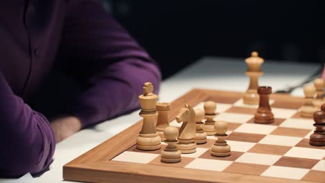 businessman plays chess on a wooden chessboard and thinks about his next chess move for his strategy