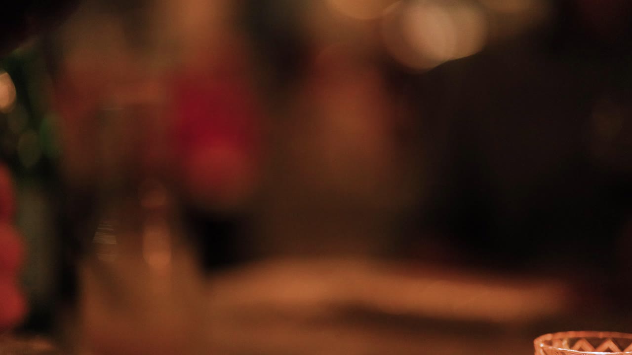 A close-up of a swirling wine glass in a dimly lit, elegant dining setting, capturing the ambiance and sophistication