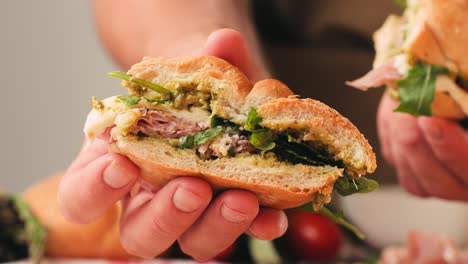 mortadella ham sandwich, traditional italian focaccia filled with thin pesto slices of mortadella, served by chef man in cafe restaurant. macro of traditional italian spanish tapas antipasti.