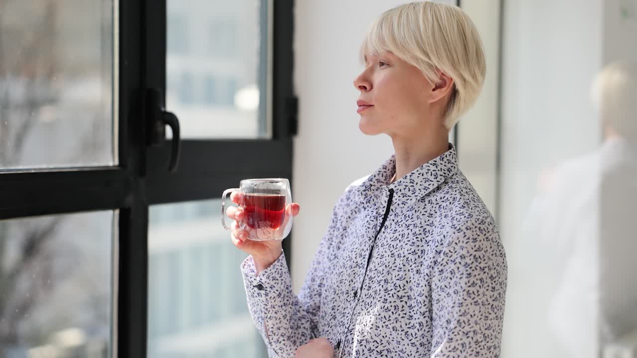 Woman daydreaming while holding tea near window