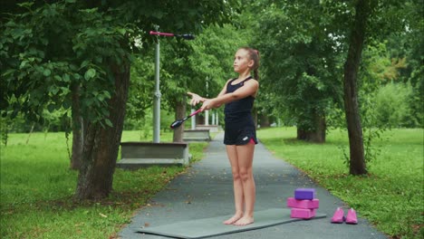 a young girl engages in outdoor physical exercise using resistance bands, showcasing strength, focus, and commitment in a natural setting