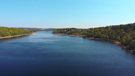 Aerial along lake and forests near Molnlycke, Sweden. Drone slow forward dolly