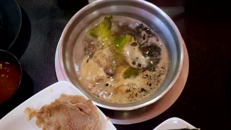 small pan with boiling soup in the buffet. boiled meat in a plate