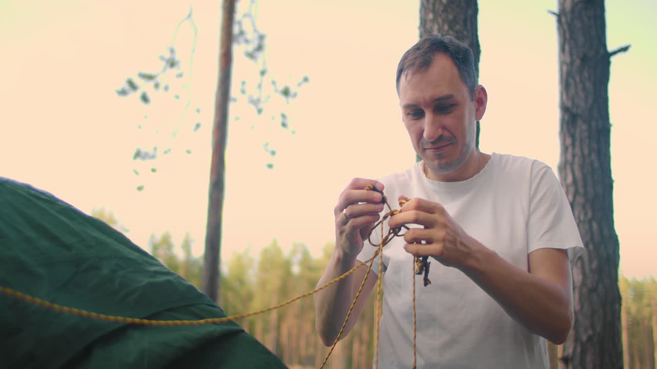 Portrait of a man setting up a tent in the woods in slow motion