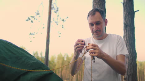 Portrait-of-a-man-setting-up-a-tent-in-the-woods-in-slow-motion