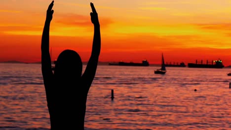 woman performing yoga on the beach