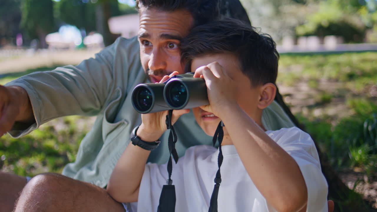 Father son looking binoculars in forest adventure enjoying birdwatching closeup