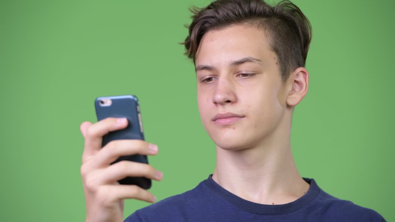 Young handsome teenage boy using phone