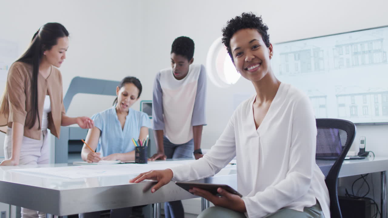 Happy african american businesswoman looking at camera with diverse colleagues in background