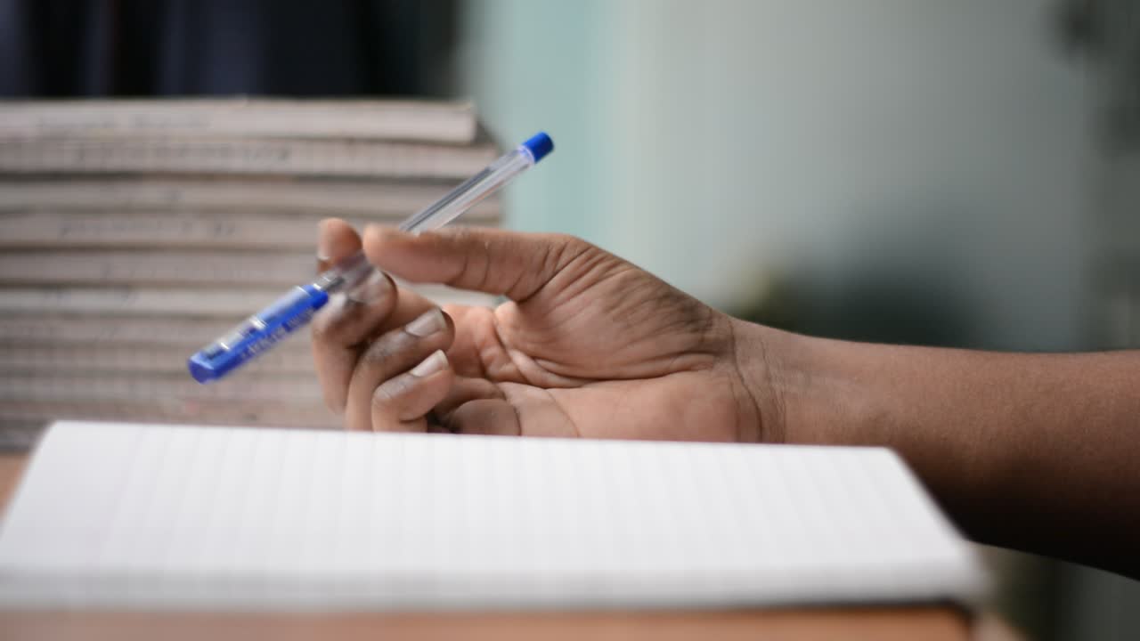 Rotating pen with hand on book while thinking to write something
