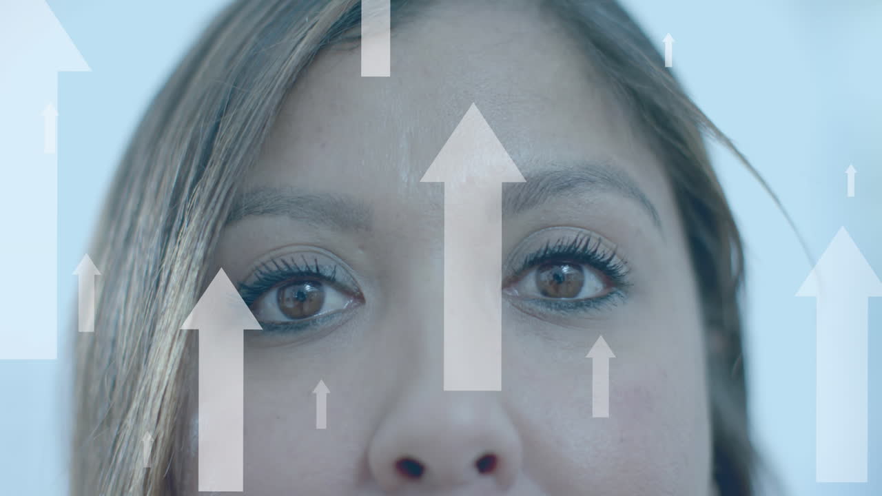 flechas de datos hacia arriba sobre los ojos de una mujer de negocios casual biracial sonriente en la oficina