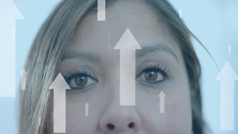 flechas de datos hacia arriba sobre los ojos de una mujer de negocios casual biracial sonriente en la oficina