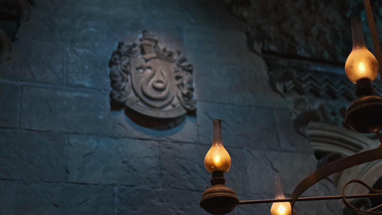조명이 켜진 전구와 고귀한 슬리데린 문장 벽 예술이 있는 골동품 램프에 초점을 맞춥니다.
