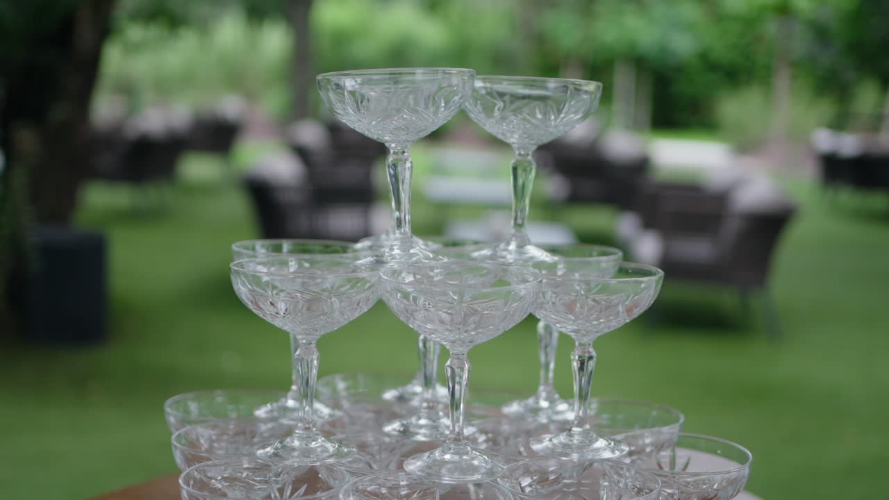 crystal glass tower stands elegantly outdoors, with blurred greenery and chairs in the background