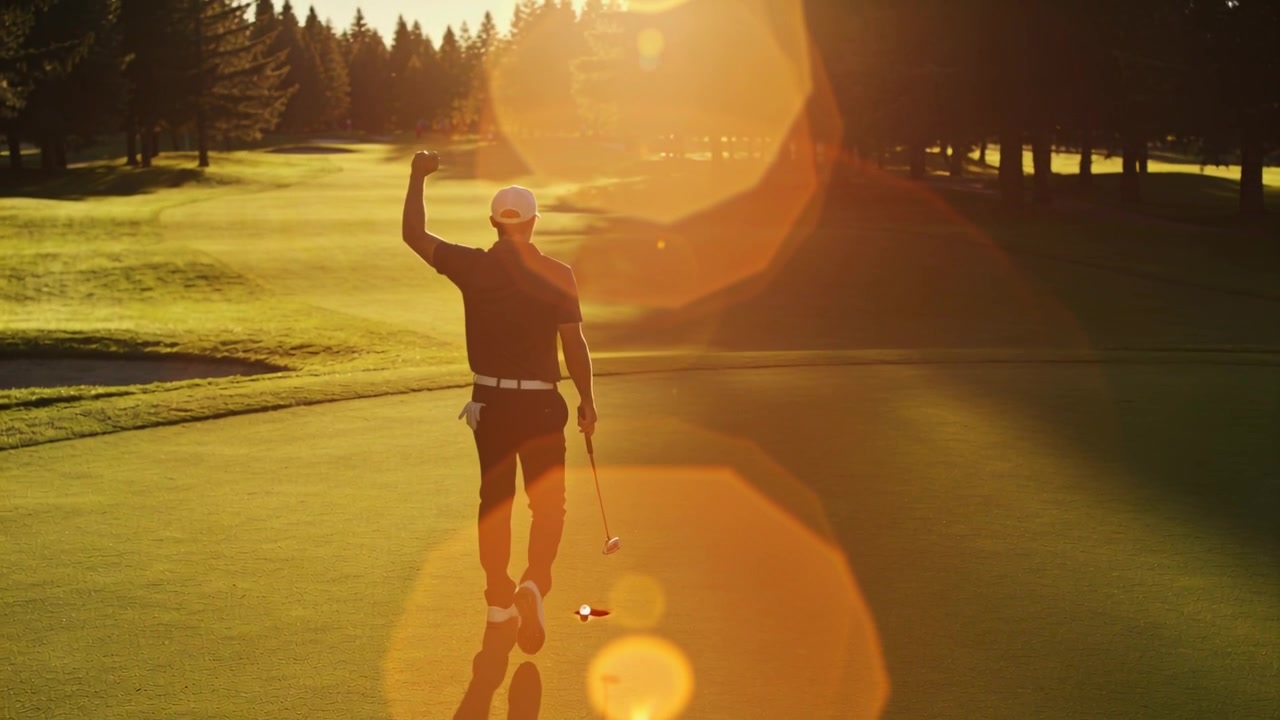 Lopend golfer met witte pet en donkere polo, die zijn vuist opsteekt na het putten op de green, met putter in de hand.