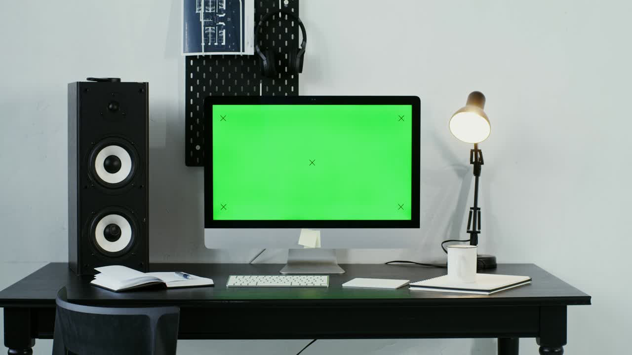 녹색 화면 을 가진 컴퓨터 모니터 가 현대적 인 인테리어 에서 검은 테이블 에 앉아 있다