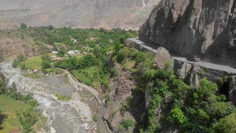 aerial over bamboret river with hillside road at kalash valley. follow shot