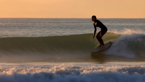 surfer riding a wave at sunrise