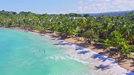 Blue-crystal-clear-water-of-Caribbean-at-Playa-Bonita,-people-swim