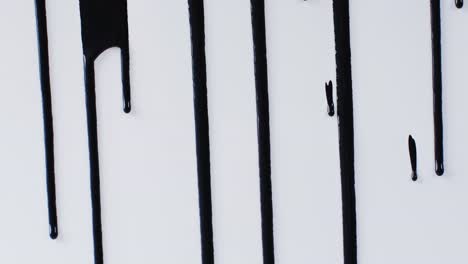 close up of black paint shapes on white background with copy space, slow motion