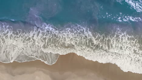 Vista-Aérea-De-La-Ola-Oceánica-En-Bucle-Que-Llega-A-La-Costa-En-La-Playa-Dorada-Tropical