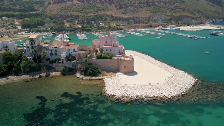 Filmato di viaggio aereo che presenta Terrasini come destinazione estiva sulla costa siciliana. Riprese con drone che catturano il porto turistico di Terrasini incorniciato dal mare aperto e dalla costa. Ampia ripresa aerea con drone che mostra