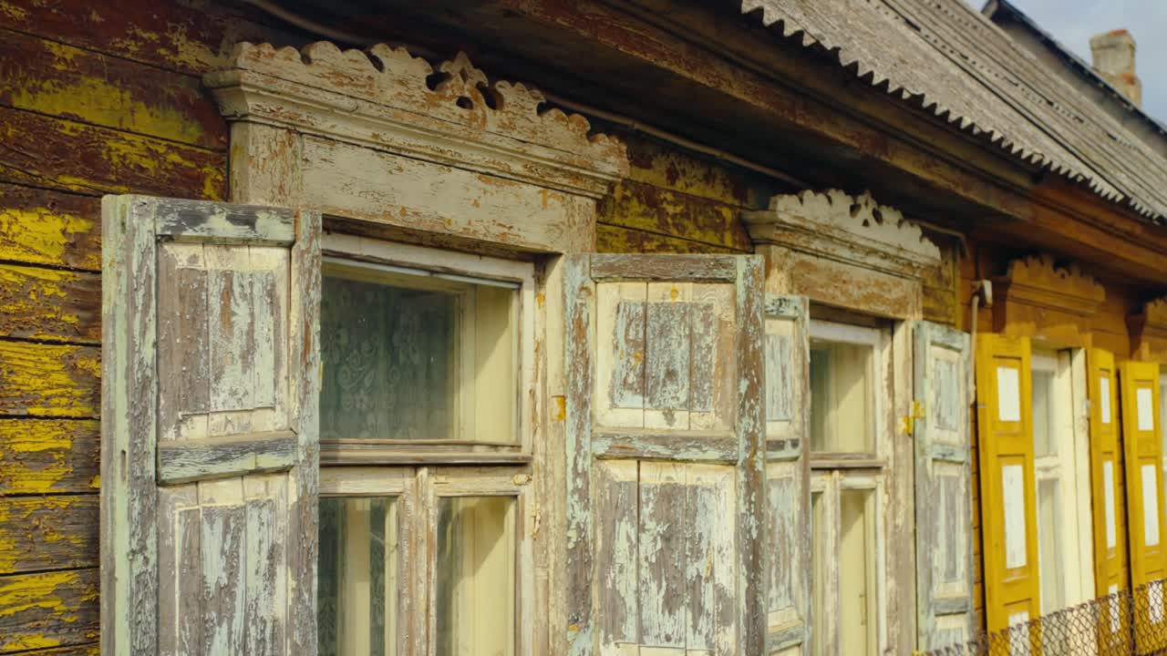 Close-up of weathered wooden windows with faded paint and intricate carvings on a traditional rural house. Location: Malutki, Latvia Malutki, Latvija