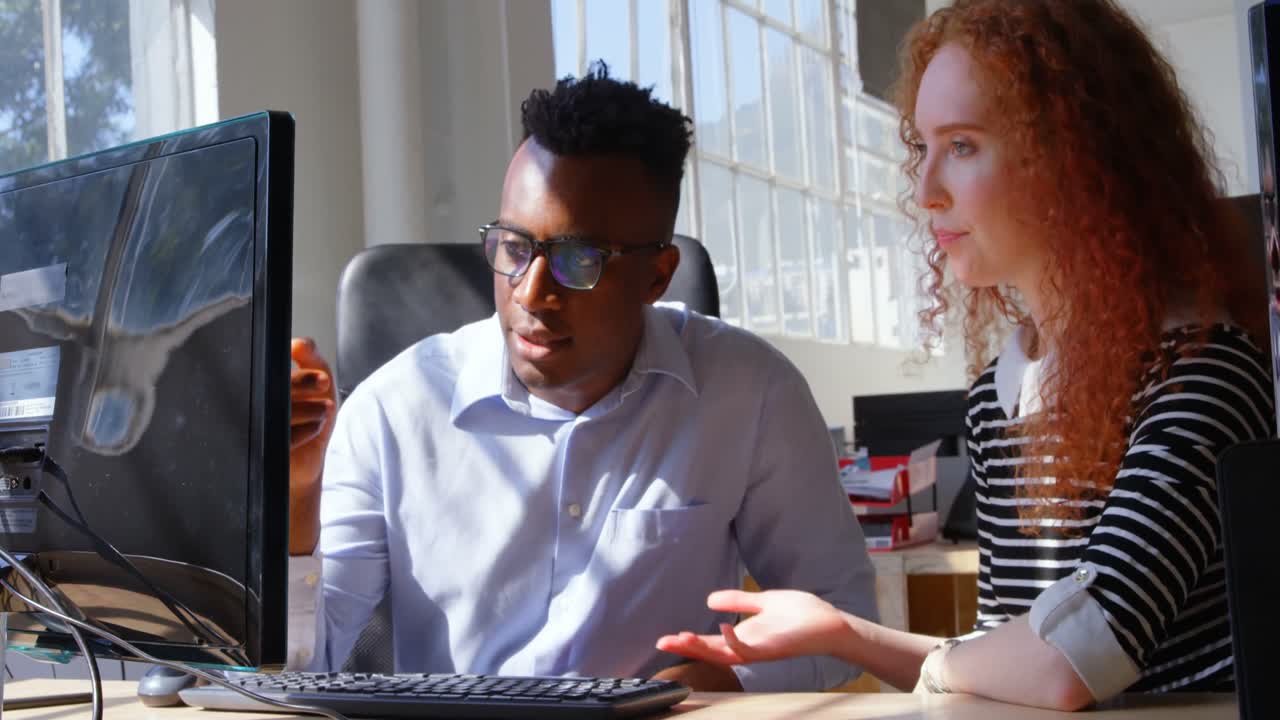 Front view of young mixed-race business team planning and working on desktop pc in modern office 4k