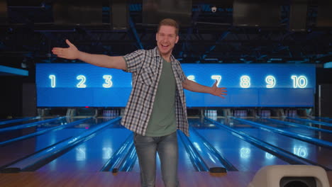 A-young-man-jumps-joyfully-looking-into-the-camera-celebrating-the-victory-in-slow-motion.-Throw-in-the-bowling-alley-to-make-a-shoot.-Victory-dance-and-jump-with-happiness.