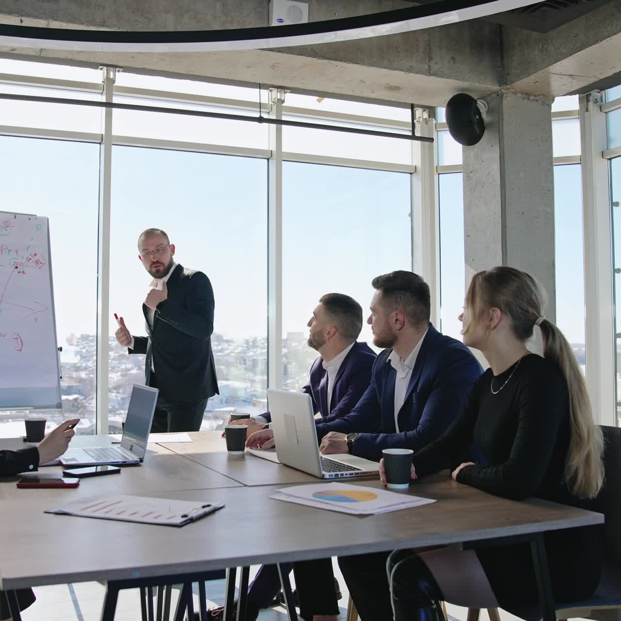 Emotional speech in front of team. Colleagues sitting at the table and listening to a man presenting chart. Business meeting in the office for coworkers