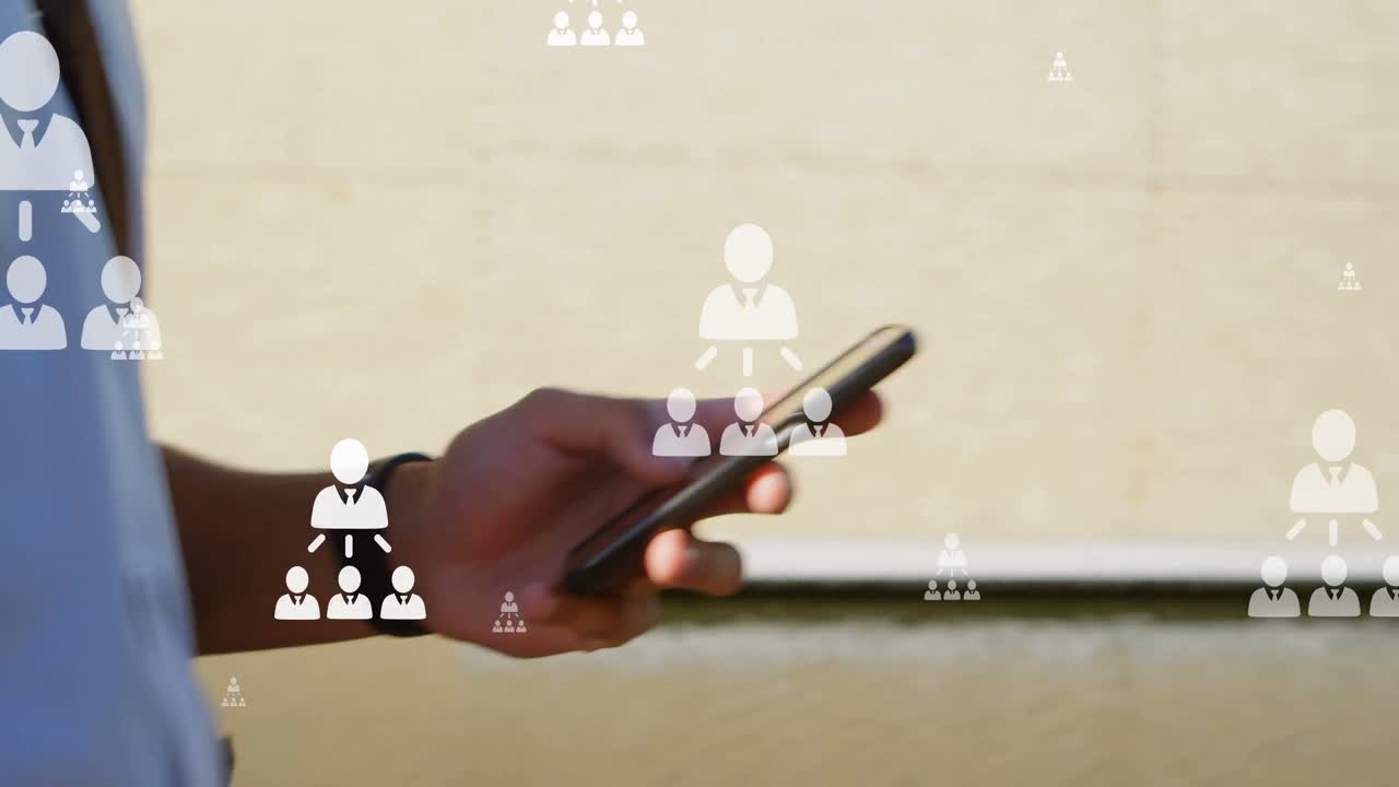 animación de iconos de usuario sobre las manos de un hombre biracial que usa un teléfono inteligente en la ciudad
