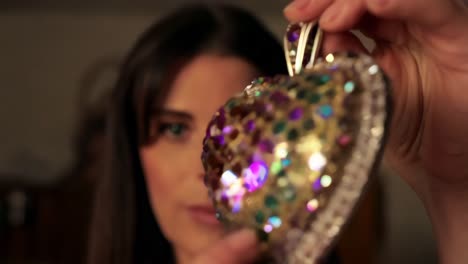 woman holding a beaded heart ornament