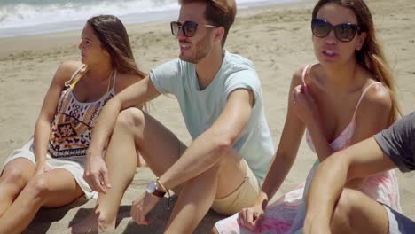 Gruppe-Von-Freunden-Sitzen-Im-Sand-Am-Strand