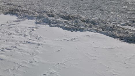 Aerial-shot-of-the-completely-frozen-river-covered-with-ice-and-snow-during-strong-winter