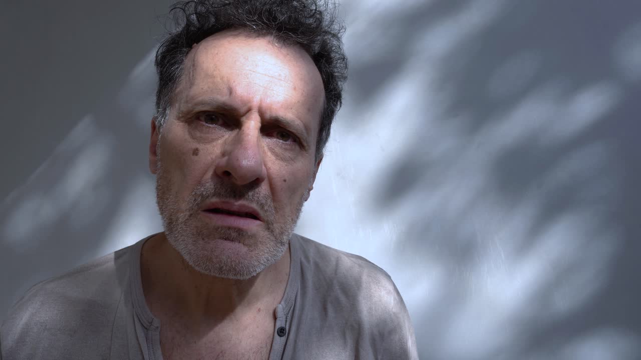 un hombre de mediana edad se sostiene la cara con ambas manos, expresando profunda preocupación o estrés