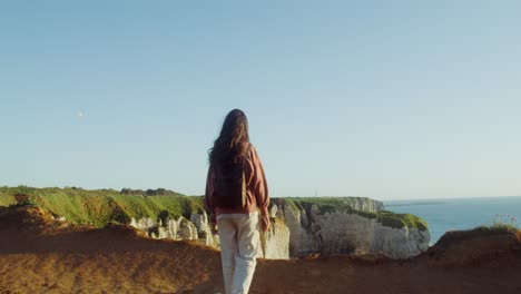 mujer caminando por los acantilados con vistas al océano