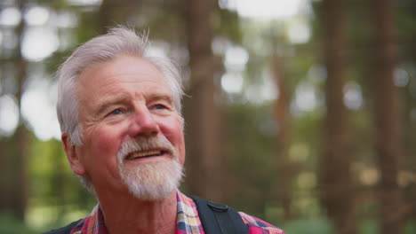 Active-Retired-Senior-Man-Walking-In-Woodland-Countryside-Wearing-Backpack