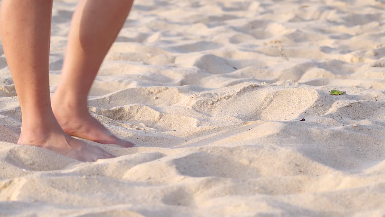 persona caminando descalza y pateando arena en la playa de karon, phuket
