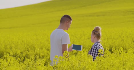 Los-Agricultores-Discutiendo-Sobre-Tablet-PC-En-El-Campo-De-Colza-4