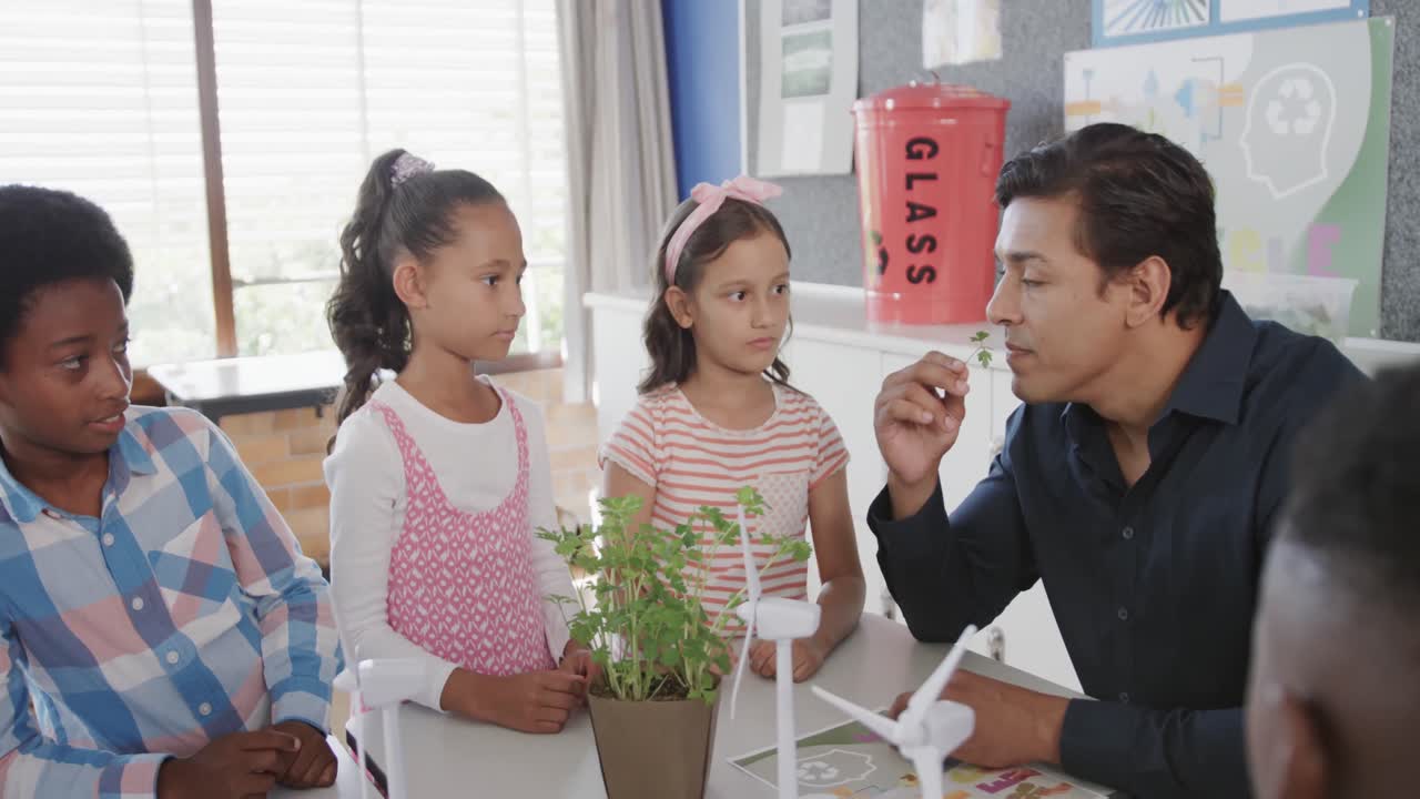 다채로운 행복한 남성 교사가 초등학교에서 학생들에게 생태학을 가르치고 있습니다.