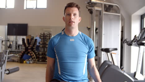 man practicing bicep curls with dumbbells at a gym, front view