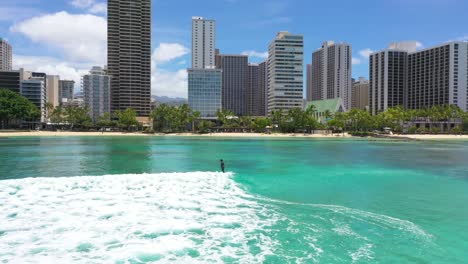 african woman surfing riding a wave at the beach, beautiful turquoise water on coast with city skyline on the background