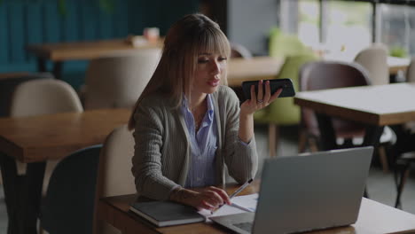 Asian-woman-recording-voice-recognition-message-on-speakerphone.-Businesswoman-using-virtual-assistant-app-sets-reminder-on-smart-phone.-Digital-ai-mobile-assistance-tech-concept.-audio-message.