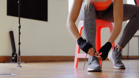 female boxer tying shoelaces in fitness studio 4k