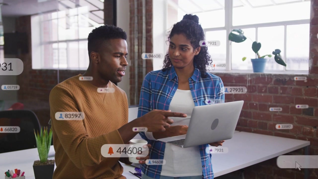 Woman scrolling laptop, man pointing, floating badges rising between them showing business metrics