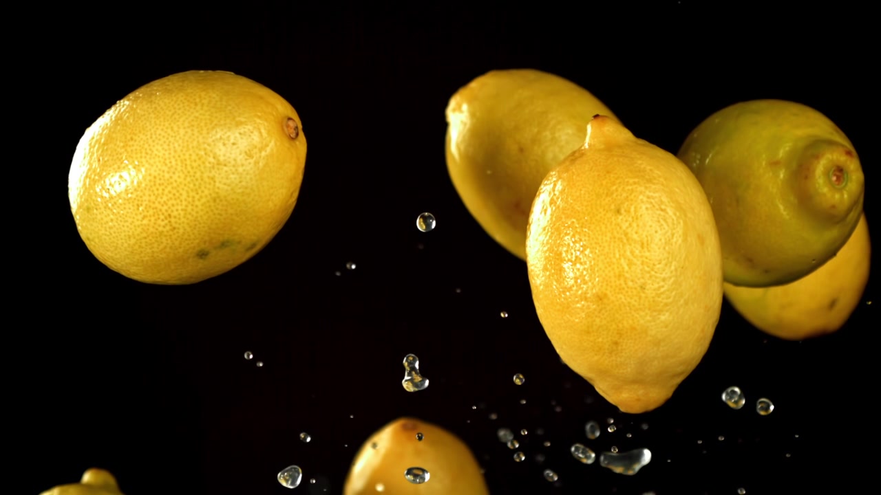 Limoni freschi con gocce d'acqua che cadono al rallentatore su sfondo nero